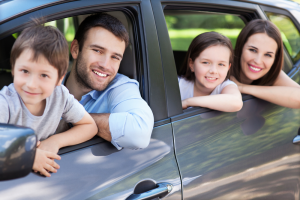 Family sitting in a car smiling out the window