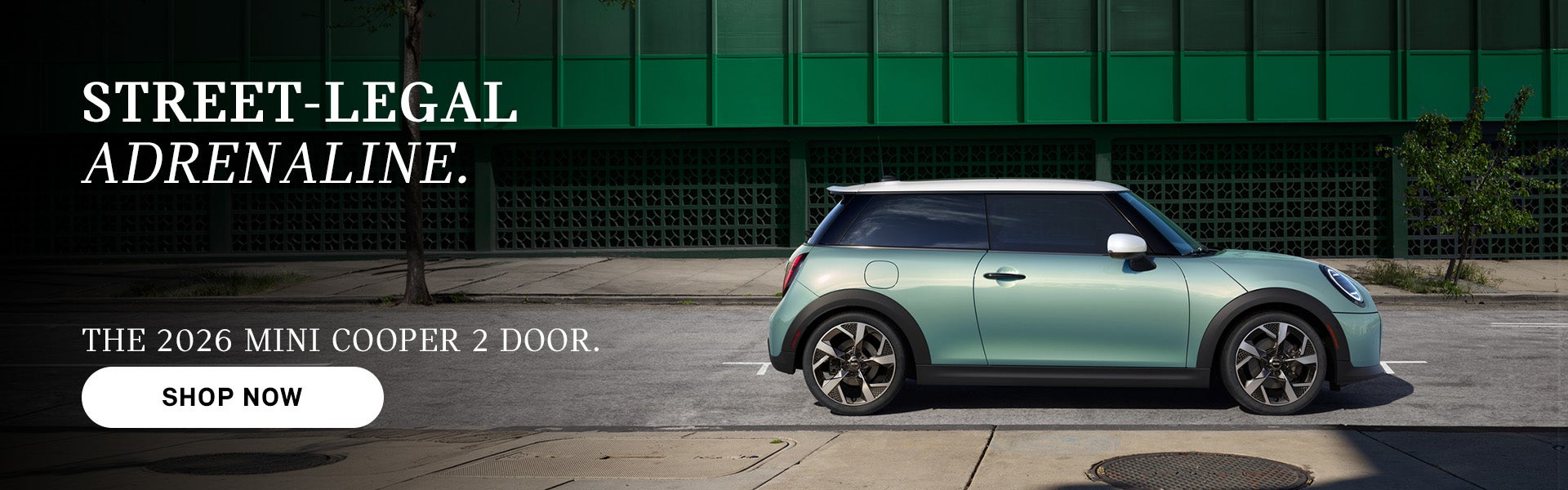 Mint green MINI Cooper 2-door parked on a city street with building backdrop, with ad text promoting the 2026 model and a “Sh