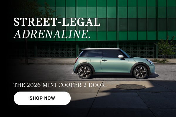 Red MINI Cooper 4-door driving on a city street, with motion blur in the background and ad text promoting the 2026 model