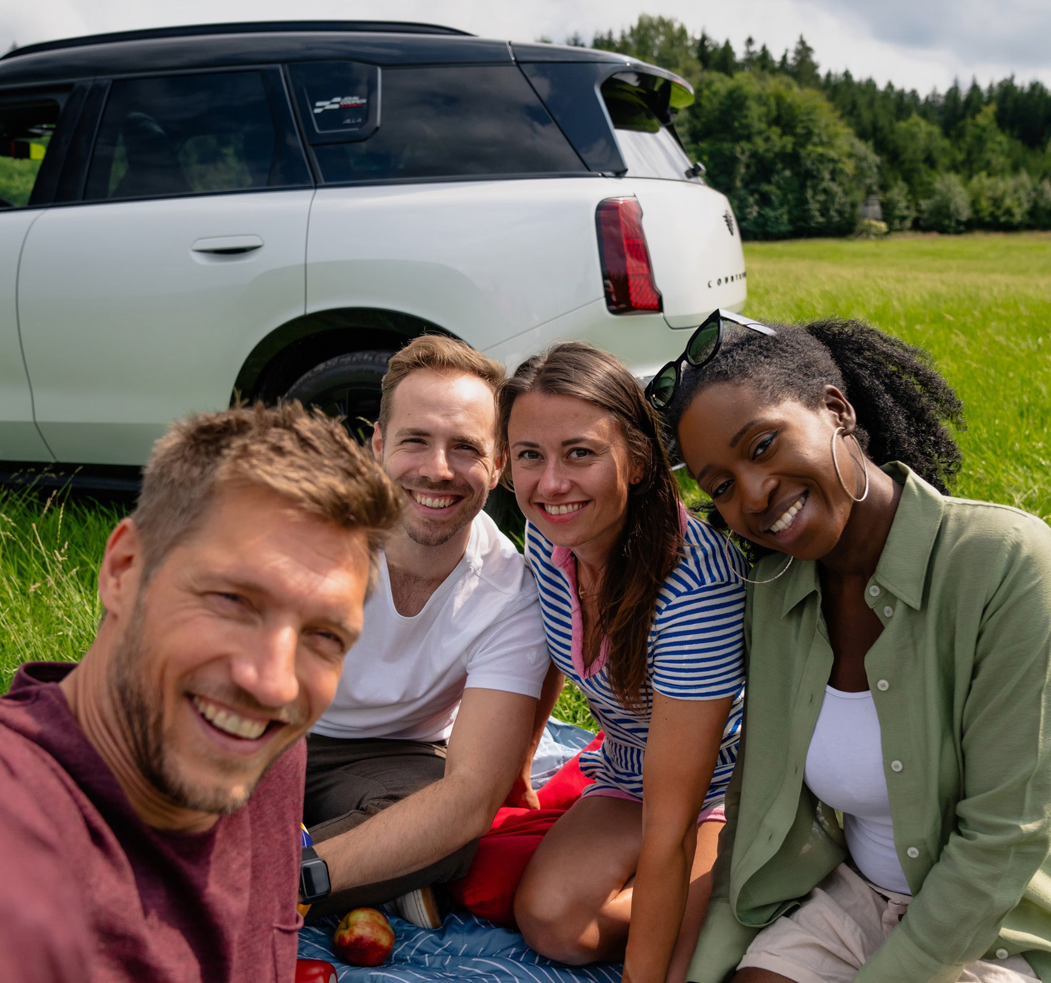 A group of friends smile in front of a MINI.